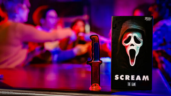 De doos van Scream the Game met mensen op de achtergrond die het spel spelen